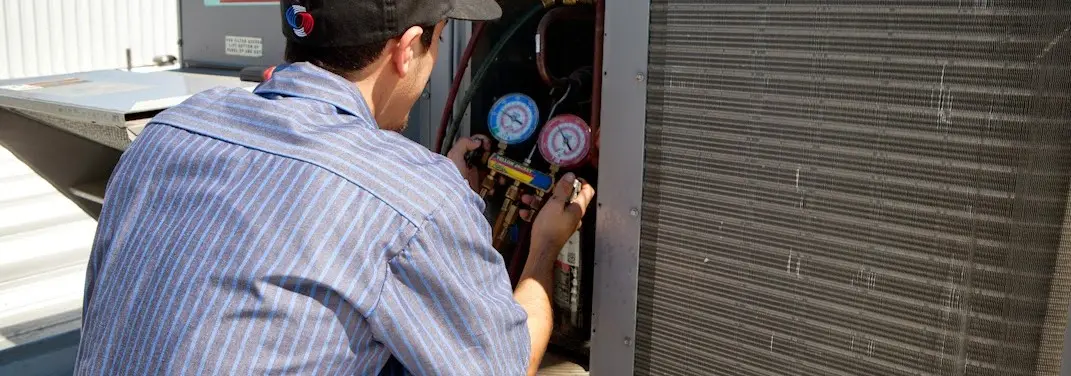 HVAC technician servicing a condenser unit in Frederick
